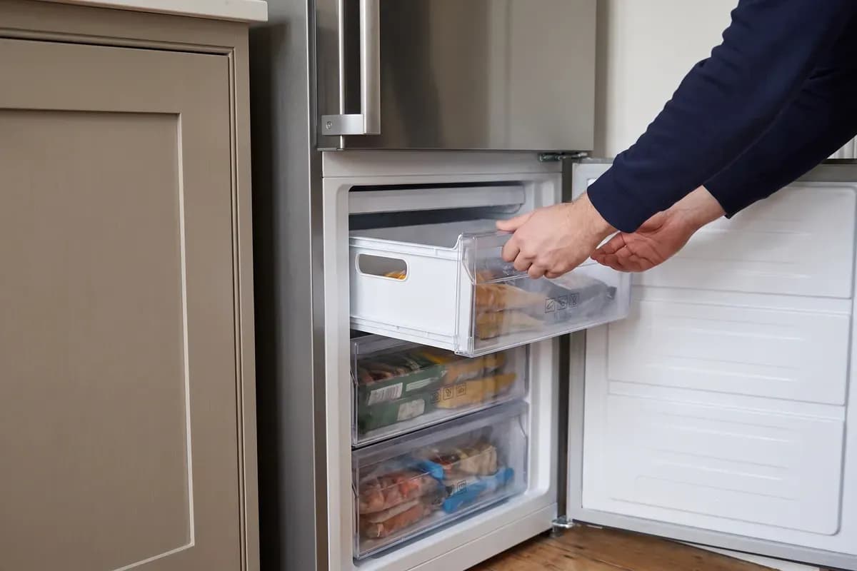 An engineer carrying out fridge freezers repairs in a customer's home